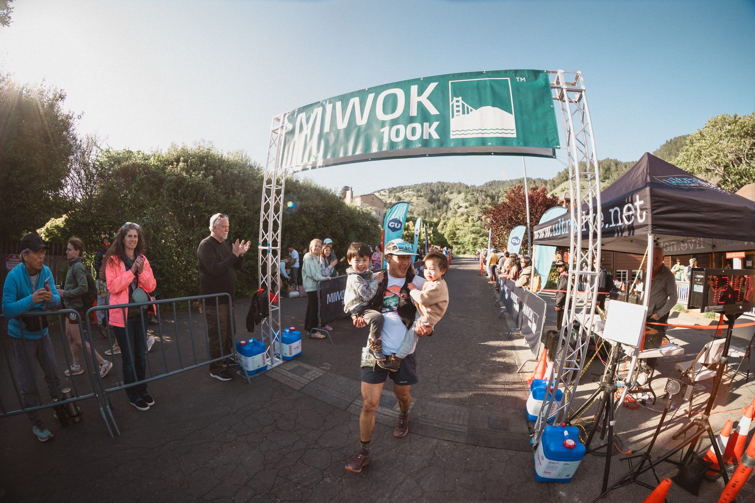 A runner carrying his two small children across the finish line. 