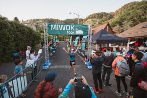 Young male runner crossing the finish line of the race with his arms outstretched. 