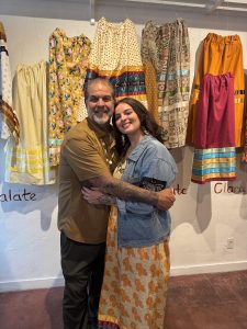 John Simons hugging his daughter Elissa in front of ribbon skirt display.