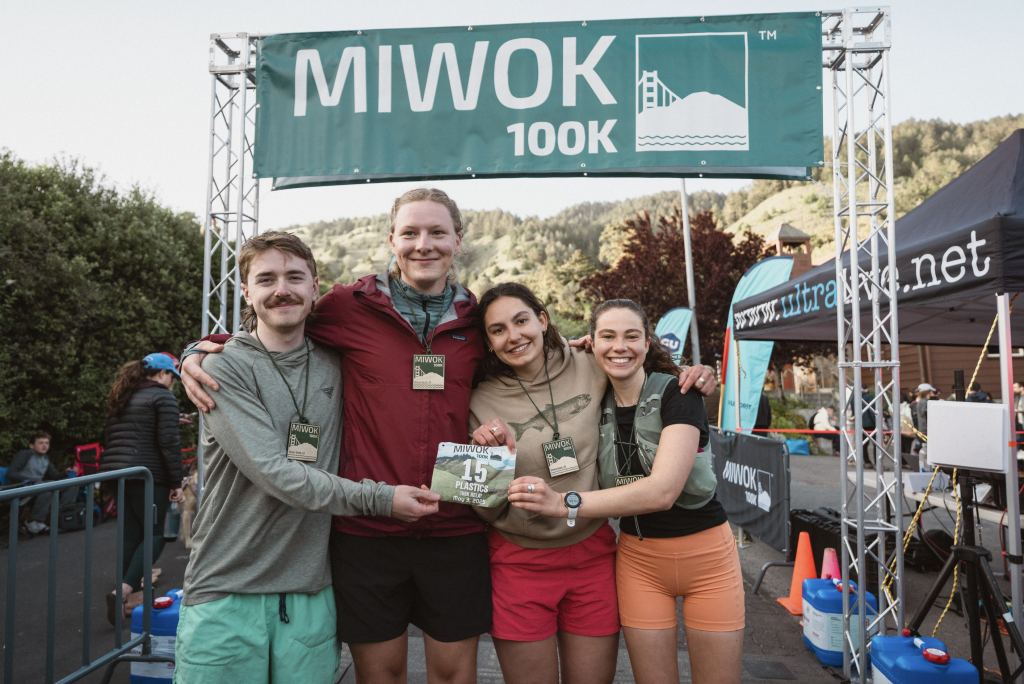 Team of four young relay runners, holding their medals at the finish line. 
